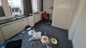 A bedroom with a bed, a radiator, a window with curtains, a desk, and a chair. - Fantastic Inn Warsaw - Jasna (Warsaw)