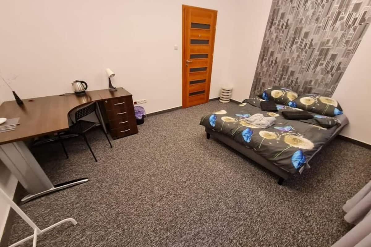 Une chambre à coucher comprenant un lit, un bureau, une chaise, une armoire et une porte.