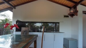 A modern kitchen with a glass-top table, white cabinets, and a built-in stove. - Sea Bloom Villa (Thalaramba)