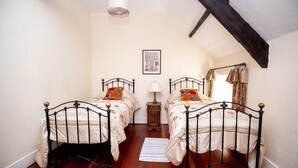 Une chambre avec deux lits simples, une table de chevet, une lampe et un tableau encadré au mur.