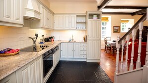 Une cuisine avec des meubles blancs, un plan de travail noir et un escalier en bois.