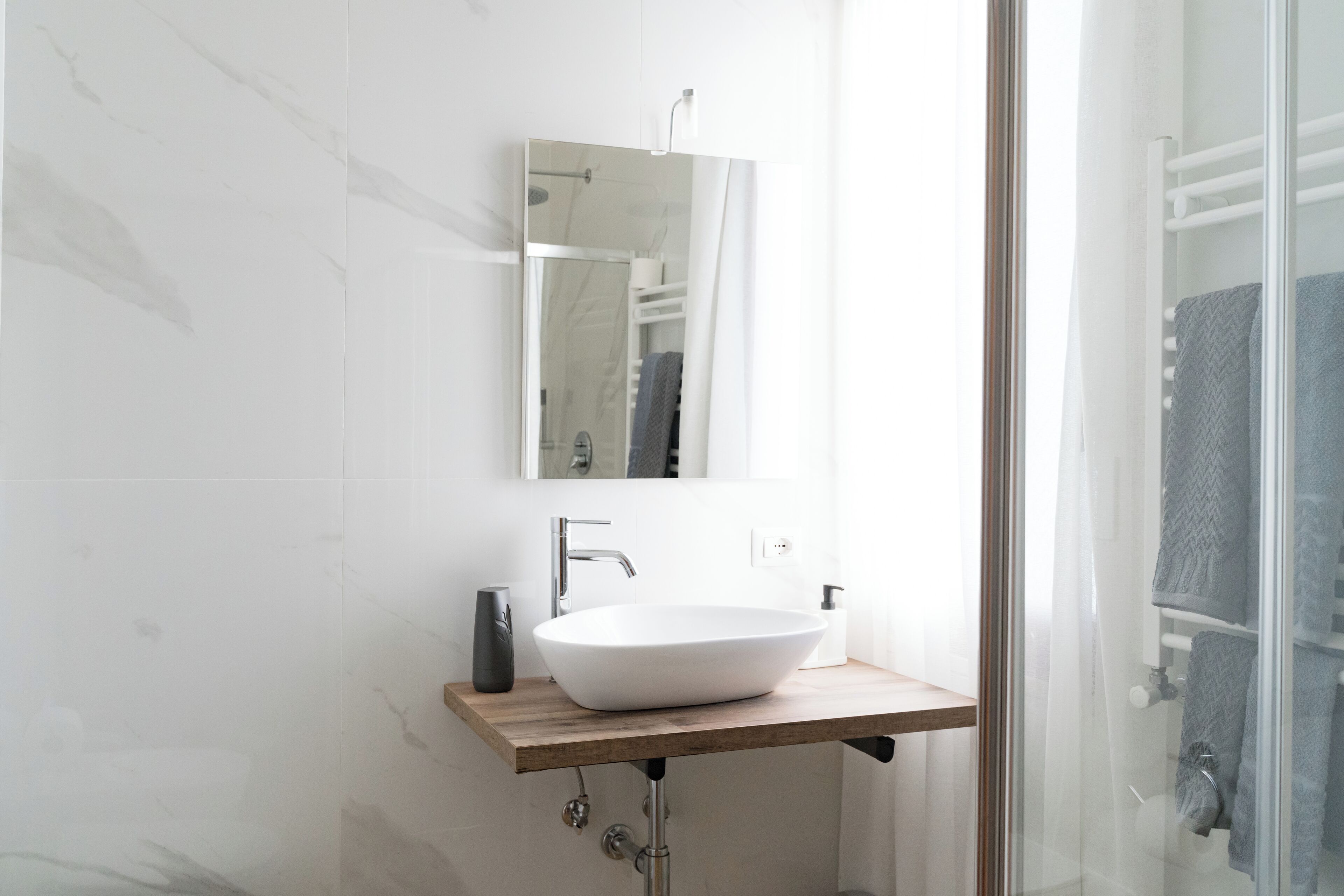 A modern bathroom with a white vessel sink, a mirror, and a glass shower enclosure.