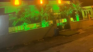 El exterior del hotel Akdeniz Suite, con señalización iluminada y un acceso ajardinado.