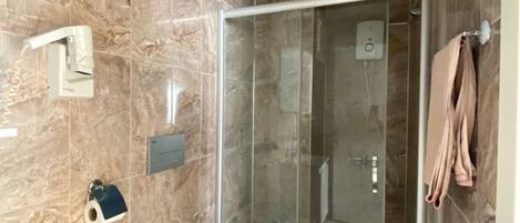 A bathroom with a glass-enclosed shower, a toilet, and a towel rack.