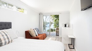 Un dormitorio con una cama grande, un sofá, una mesita y vistas a un balcón con mesa y sillas.
