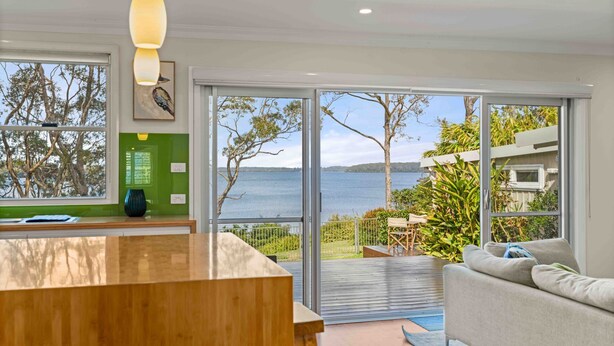 Una cocina moderna con un amplio ventanal que da a un lago, un comedor con vistas y una zona de estar acogedora, también con vistas.