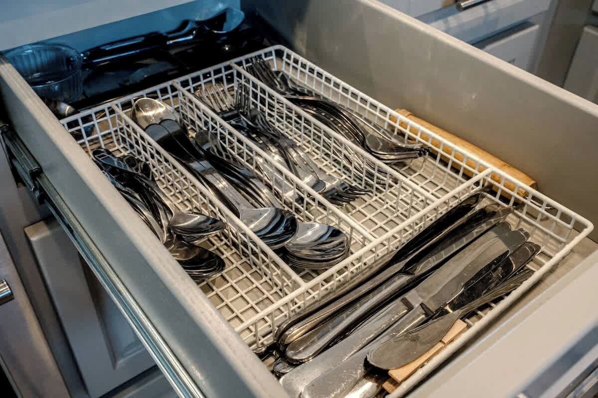 Astianpesukone, joka on täynnä erilaisia astioita ja ruokailuvälineitä.