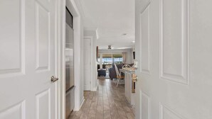 A hallway with white doors, a kitchen area, and a seating area with a view. - Renovated Lakefront Escape w/ Amazing Views (Garland County)