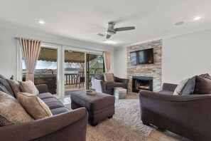 A living room with a fireplace, a ceiling fan, and a TV mounted on the wall.