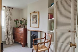 A room with a wooden dresser, a chair, a fireplace, a framed portrait, and a bookshelf. - No.2 Coastguards Cottage, welcoming holiday home near the coast (West Lulworth)