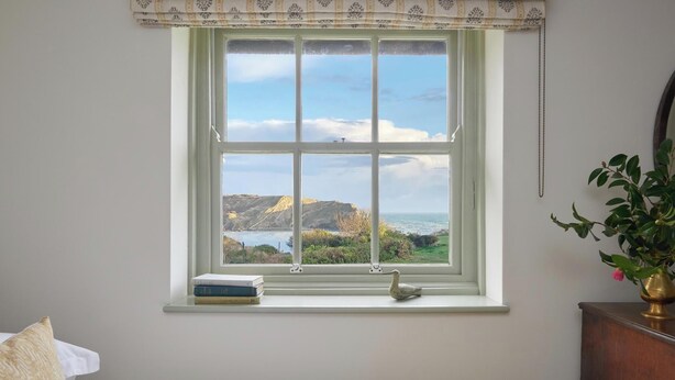 A bedroom with a large window overlooking a scenic landscape. - No.2 Coastguards Cottage, welcoming holiday home near the coast (West Lulworth)