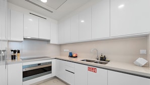 A modern kitchen with white cabinets, a stainless steel sink, and a built-in oven. - 2BR M CF7B Pet Friendly Stay (Dubai)