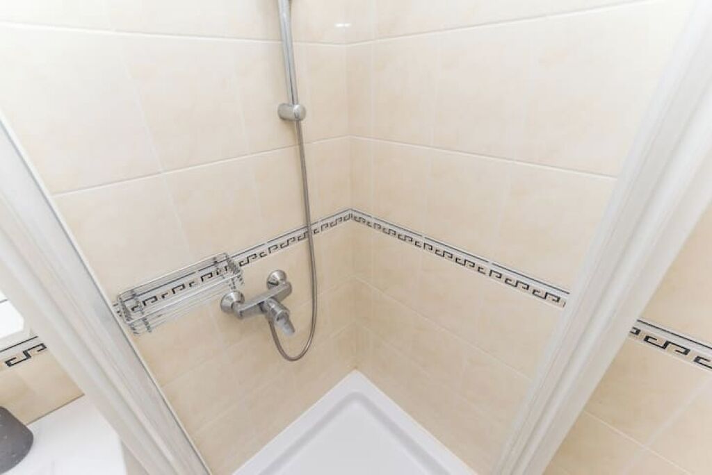 A small, enclosed shower area with a showerhead and control panel.