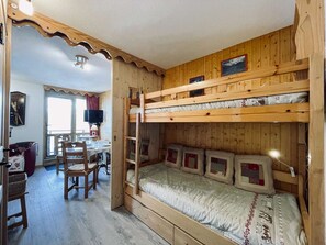 A cozy cabin with a bunk bed, a dining area with a table and chairs, and a television. - Cozy chalet-style studio near slopes with balcony (Les Belleville)
