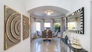 A modern dining area with a glass-top table, four chairs, and a chandelier. - Villa Renata ZadarVillas (Zaton)