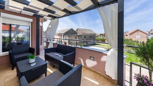 A covered outdoor seating area with wicker furniture and a view of neighboring houses. - Villa Renata ZadarVillas (Zaton)