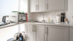 Una cocina moderna con horno empotrado, cafetera, lavabo y ventana que proporciona luz natural.