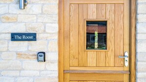 A wooden door with a small window, a metal handle, and a sign reading "The Roost" on the wall. - The Roost: a riverside retreat (Stamford)