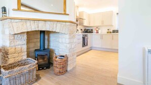 A modern kitchen with white cabinets, a stone fireplace, and a black stove. - The Roost: a riverside retreat (Stamford)
