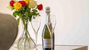 A bottle of Prosecco wine and two wine glasses on a table with a vase of roses. - The Sett: cosy riverside home (Stamford)