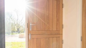 Une porte en bois, dotée d’une poignée et d’un loquet, qui donne sur un espace extérieur avec de l’herbe et des arbres.