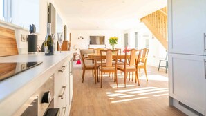 Une cuisine moderne avec des meubles en bois, une table à manger avec des chaises et un escalier menant à un étage supérieur.