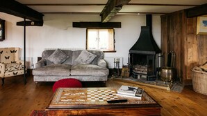 Een gezellige woonkamer met een bank, een open haard, een schaaktafel en een kamerbreed tapijt.