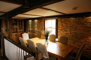 A dining area with a wooden table and chairs, stone walls, and a view of the outdoors. - Fletland Mill: 18th century mill near Stamford (Stamford)