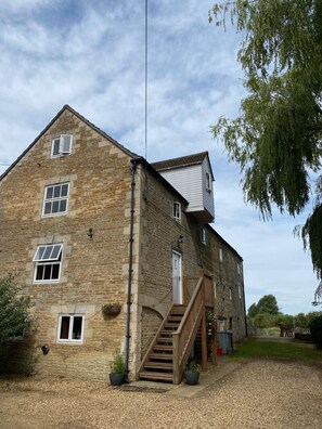 A stone building with a wooden staircase and a small garden area. - Fletland Mill: 18th century mill near Stamford (Stamford)
