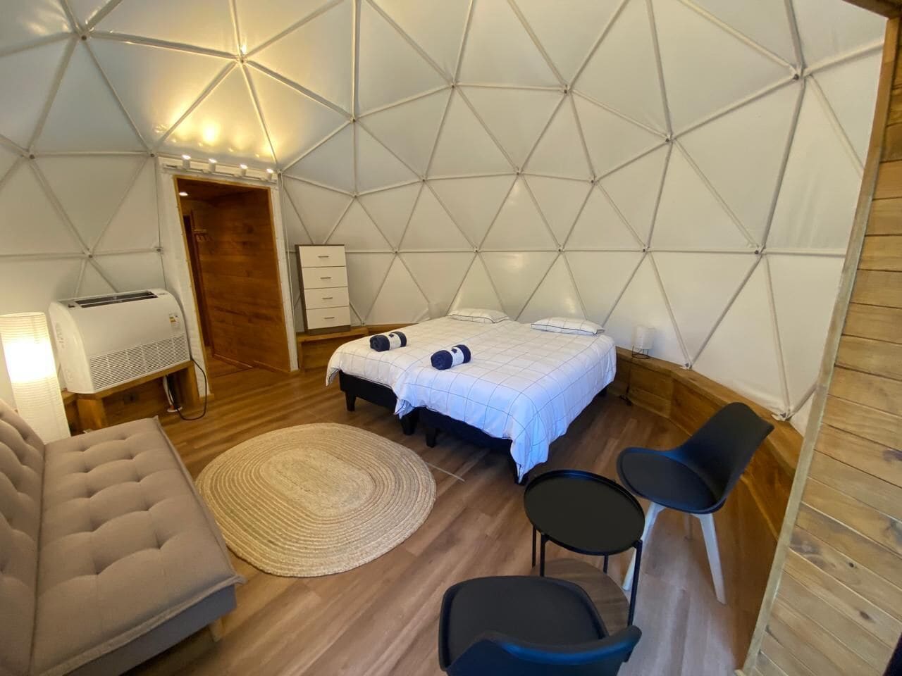 A tent-style room with two beds, a sofa, a small table, and a chair.