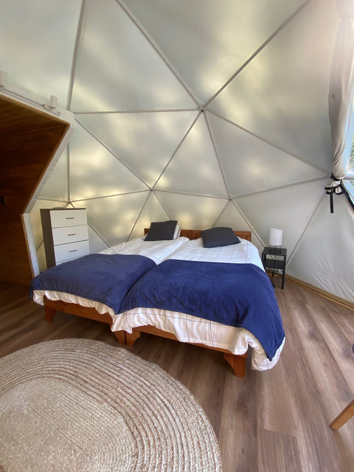 Una habitación con carpa, dos camas, una mesita y una silla.