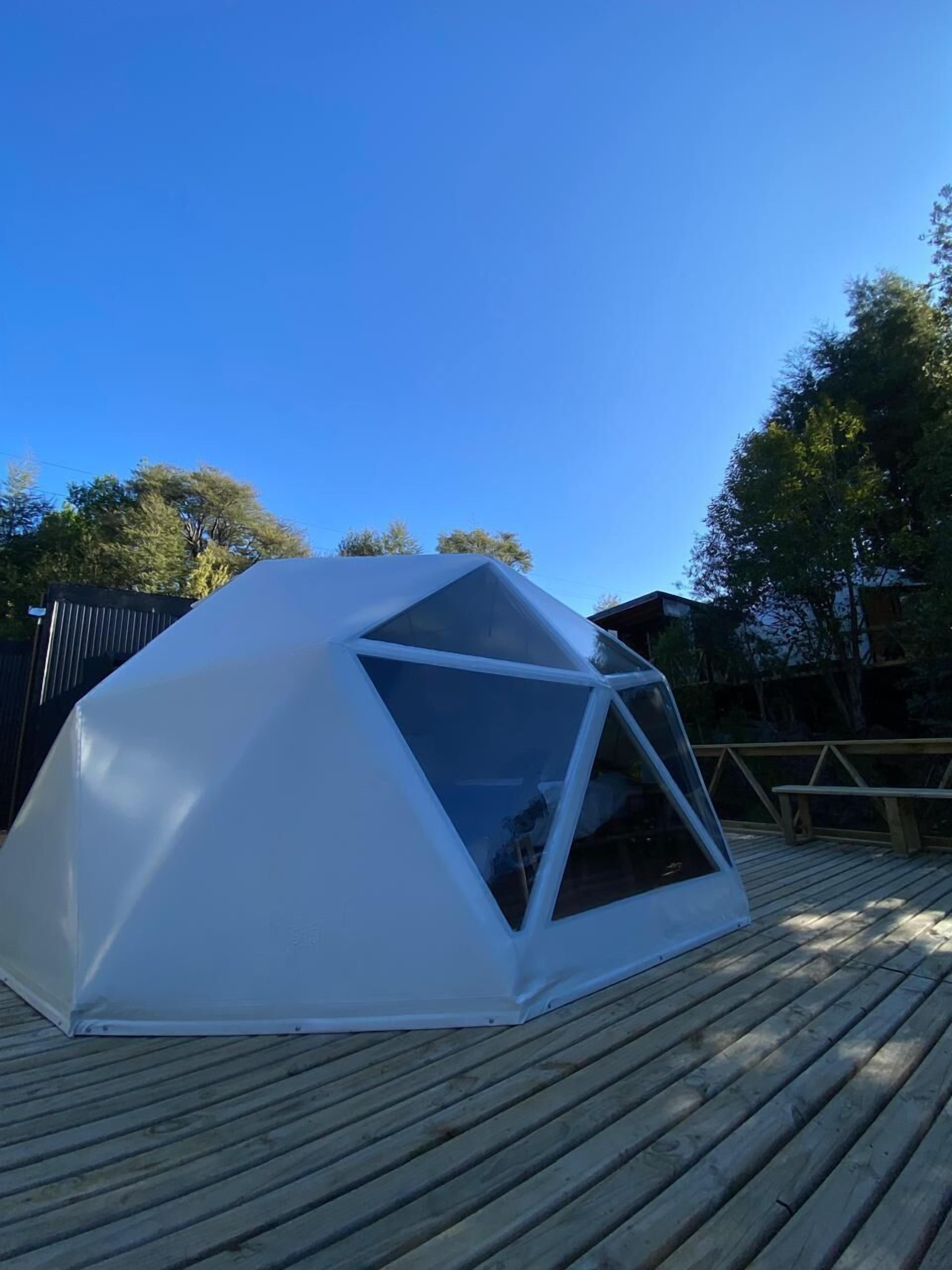 Una tienda en forma de domo geodésico sobre una terraza de madera.