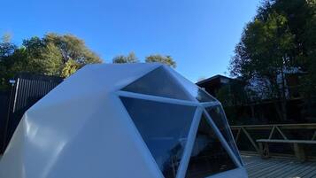 Una tienda en forma de domo geodésico sobre una terraza de madera.