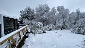 A snow-covered outdoor area with a wooden deck and a building with large windows. - HuellaBlanca Domos (Curacautin)