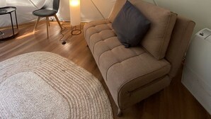 A tent interior with a sofa, chair, lamp, and a round rug. - HuellaBlanca Domos (Curacautin)