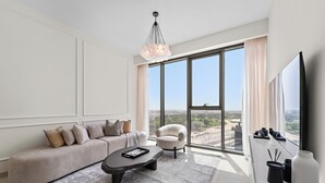 Una sala de estar moderna con un sofá, una mesa de centro y una silla. Hay un ventanal con vistas a la ciudad.