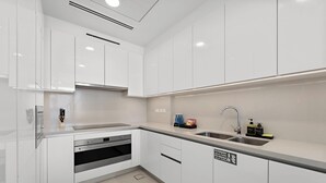Una cocina moderna con armarios blancos, electrodomésticos de acero inoxidable y horno empotrado.