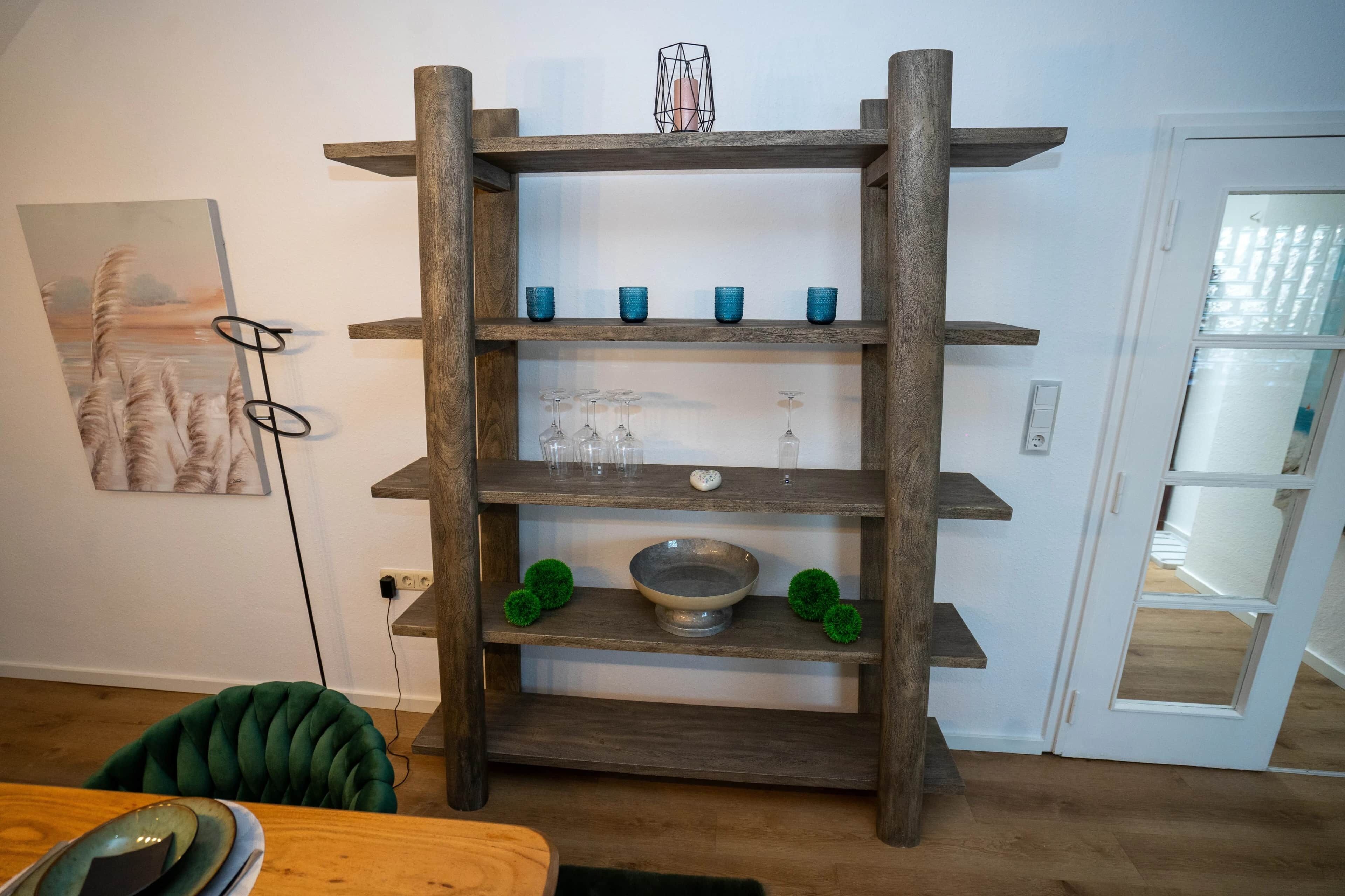 Un estante de madera con varios niveles que exhibe cristalería y objetos decorativos.