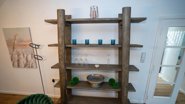 Ein mehrstufiges Holzregal mit Glaswaren und Dekorationsobjekten.
