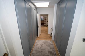 Un couloir étroit avec des armoires grises, un plancher en bois et un tapis à motifs.
