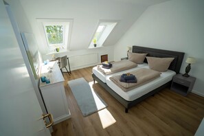 Une chambre avec deux lits, un bureau, une chaise, un radiateur et une fenêtre donnant sur un paysage verdoyant.