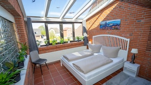 Ein Schlafzimmer mit Dachfenster, einem Bett, einem Sessel und Topfpflanzen.
