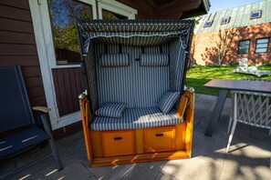 Un espace extérieur abrité, aménagé avec des coussins à rayures et un banc en bois.