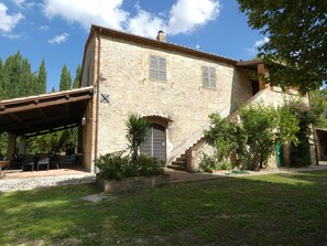 A stone building with a covered patio area, a staircase leading to the entrance, and a garden with potted plants. - Scappo in Umbria, Il Maraldo (Narni)