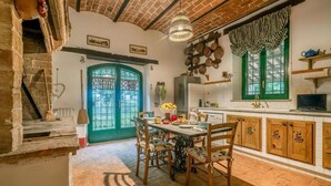 A rustic kitchen with a brick ceiling, wooden cabinets, and a dining table with chairs. - Scappo in Umbria, Il Maraldo (Narni)
