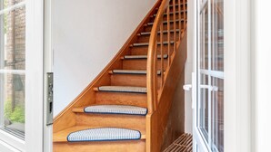 A wooden staircase with patterned carpeted steps and a metal handrail. - Apartment 2, Upper Floor with Wi-Fi (Hooksiel)