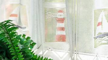 A window with a white lace curtain featuring a lighthouse design.