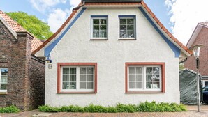 A two-story house with a white exterior, red brick chimney, and two windows with white frames. - Apartment 2, Upper Floor with Wi-Fi (Hooksiel)