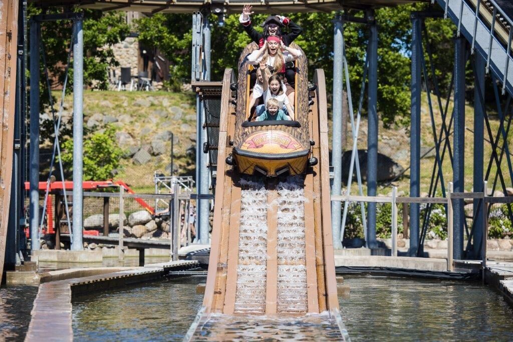 A water slide with a pirate-themed figure at the top, a metal structure, and a rocky hillside in the background.