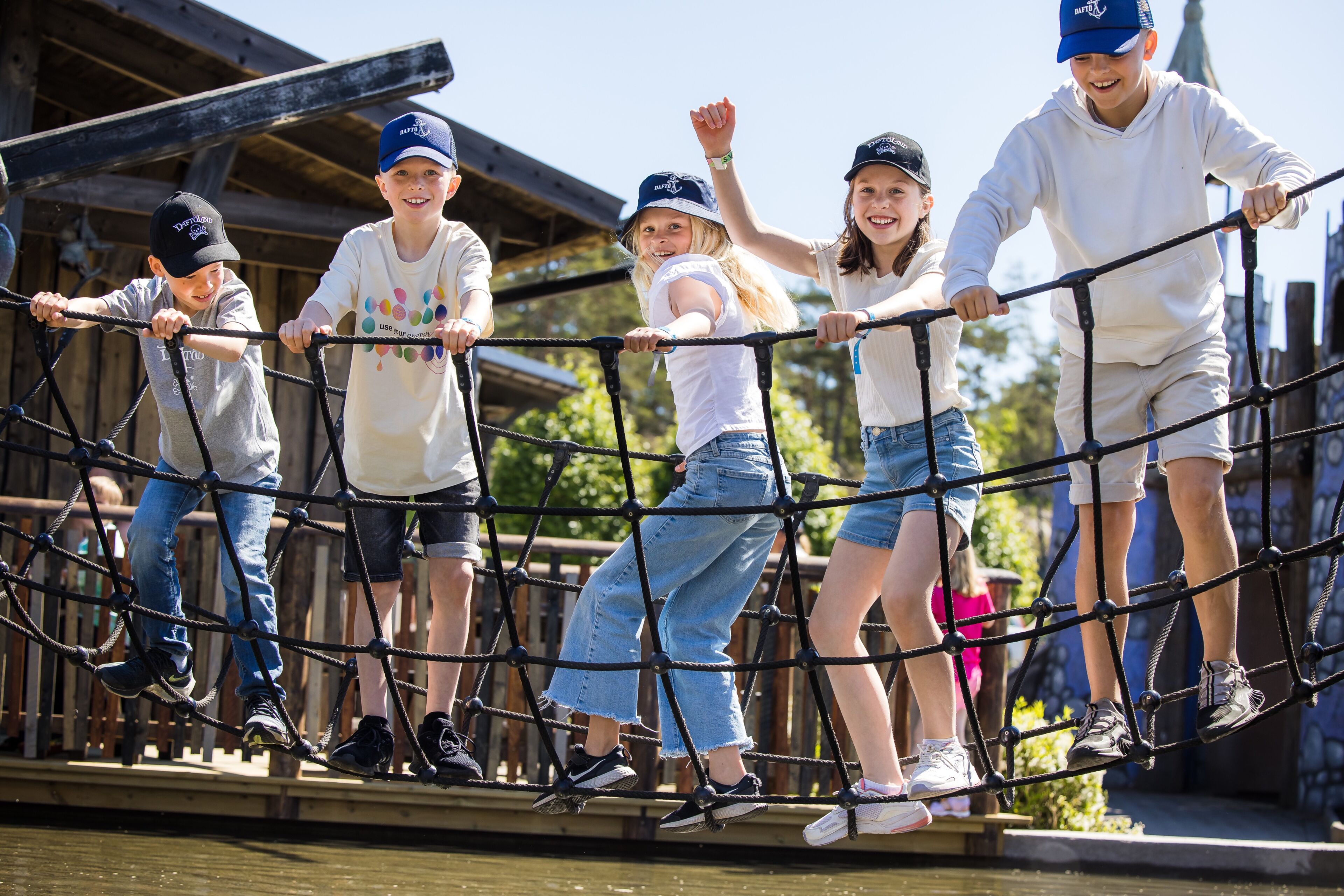 A group of children crossing a rope bridge outdoors.